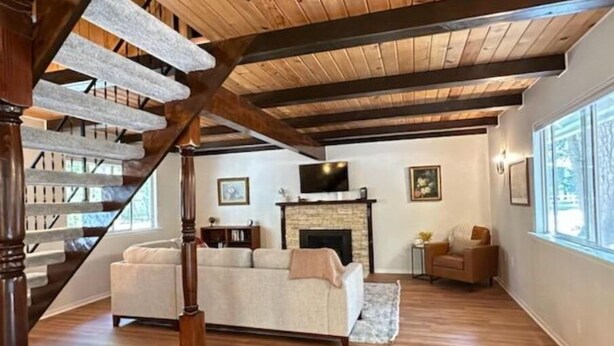 Un salon spacieux avec un escalier en bois, une cheminée et une grande fenêtre qui laisse entrer la lumière naturelle.