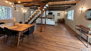 Une cuisine spacieuse avec un plafond en bois, un coin repas avec une table et des chaises, et un escalier menant à un autre niveau.