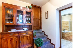 Traditional cabinet houses ceramic items, a wooden bench, and a potted plant.