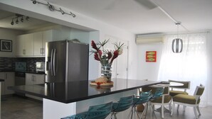 Una cocina moderna con una isla grande, electrodomésticos de acero inoxidable y taburetes de bar.