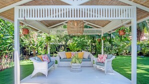 A covered patio with wicker furniture and a hanging light fixture. - Casa Agogó - Carribean house/pool/steps from beach (Puerto Viejo de Talamanca)