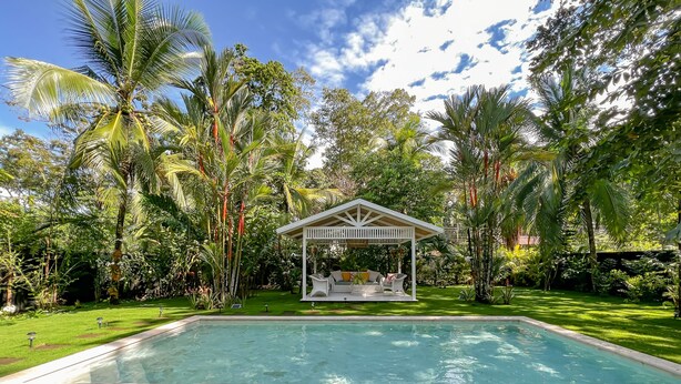 A pool area with lounge chairs, a gazebo, and lush tropical vegetation. - Casa Agogó - Carribean house/pool/steps from beach (Puerto Viejo de Talamanca)