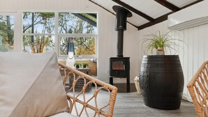 Une pièce chaleureuse avec des fauteuils en osier, un grand tonneau noir et un poêle à bois.