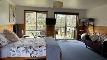 A bedroom with a bed, a sofa, a TV, and a balcony with outdoor furniture.