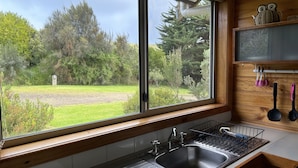 A kitchen with a large window, a sink, and wooden cabinets.