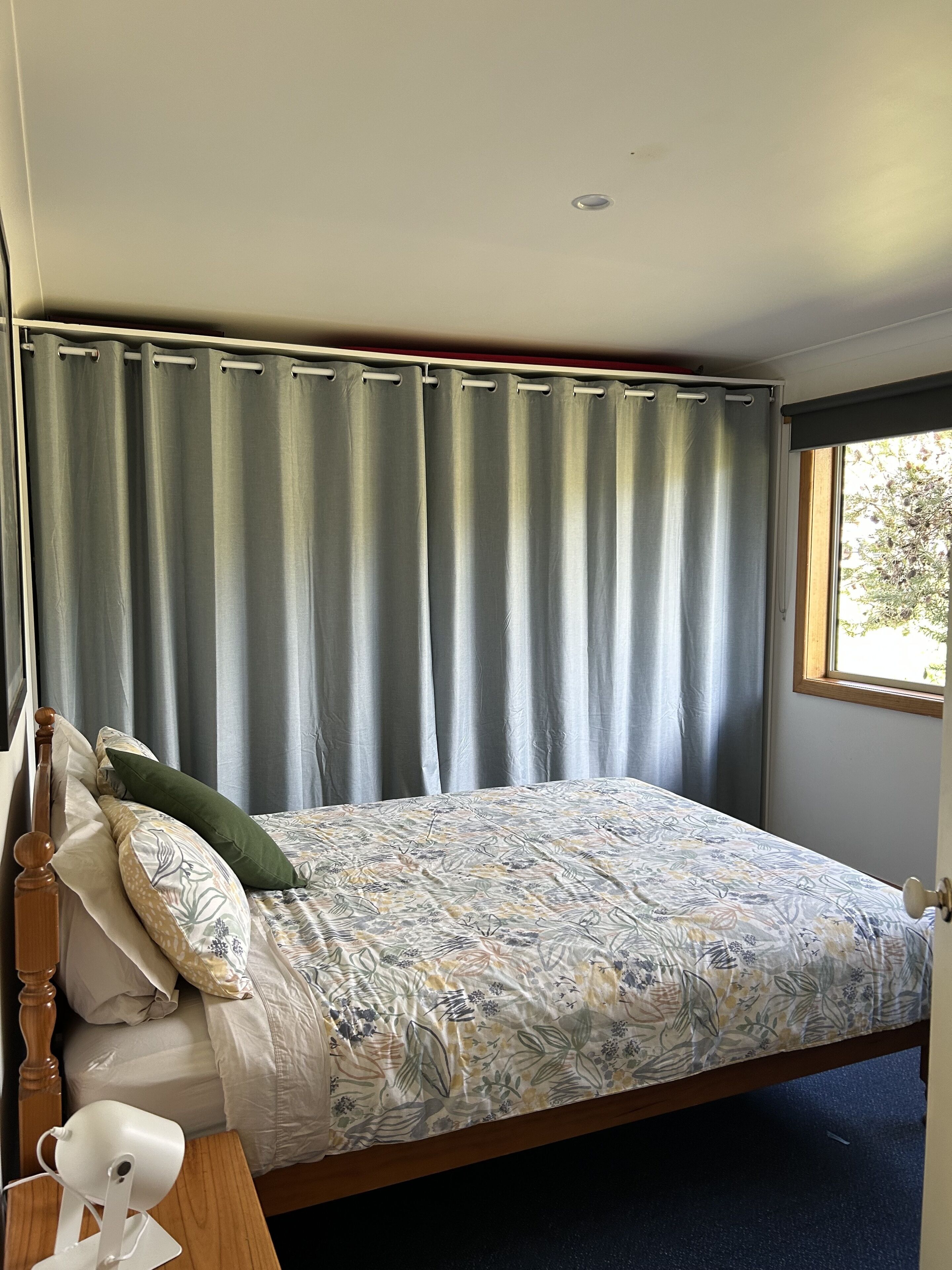 A bedroom with a bed, a nightstand, a lamp, and a window with curtains.