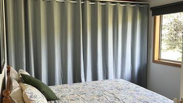 A bedroom with a bed, a nightstand, a lamp, and a window with curtains.