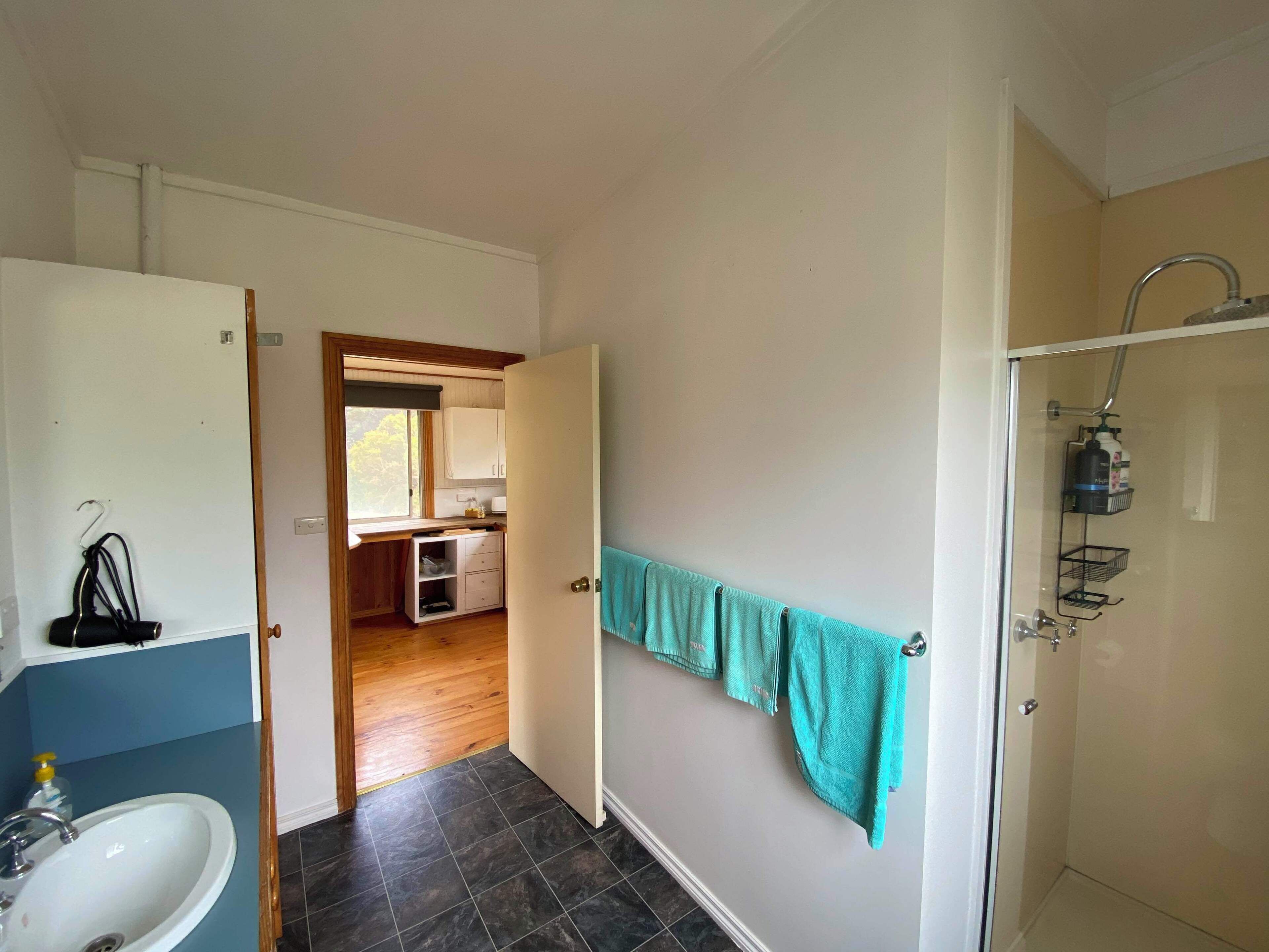 A bathroom with a sink, a shower, and a towel rack.