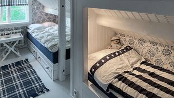 A bedroom with a bunk bed, a desk, and a window with a checkered curtain.