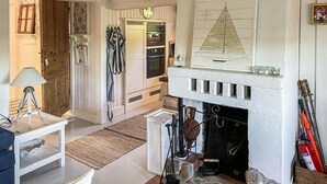 A cozy living room with a fireplace, a clock, and a sailboat painting.