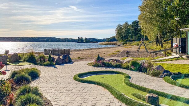 A landscaped garden with a paved pathway, a wooden bench, and a view of a lake.