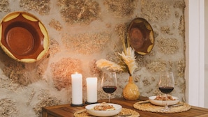 A wooden dining table with placemats, candles, and wine glasses.