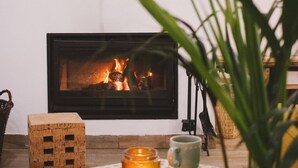 A cozy living room with a fireplace, a small table with a candle, and a television mounted on the wall.