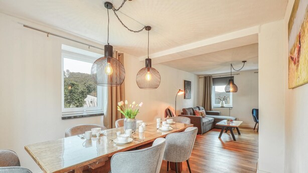 A modern dining area with a wooden table, grey upholstered chairs, and pendant lighting. - Beautiful home in Nimsreuland with WiFi (Nimsreuland)