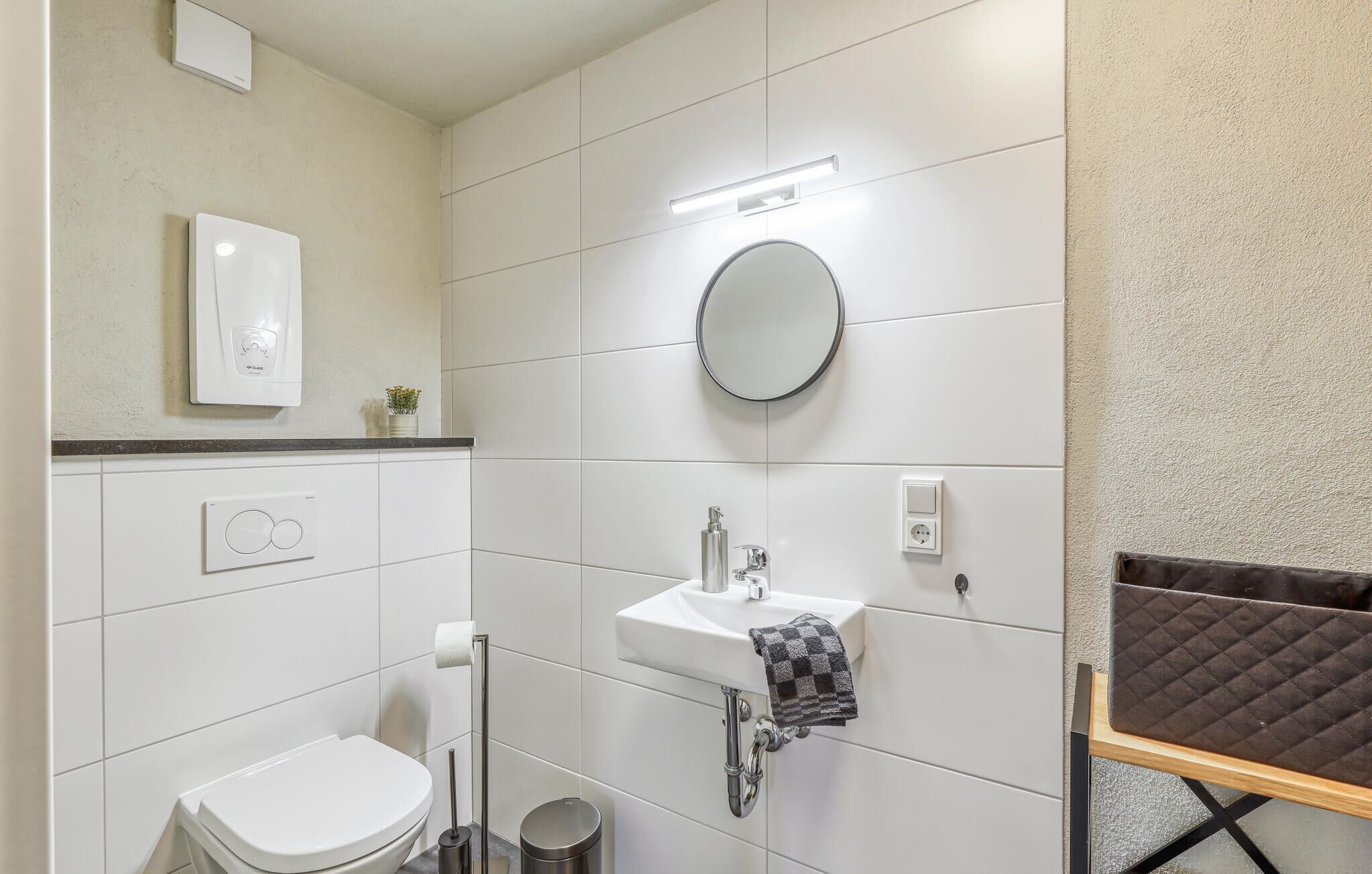 Un bagno moderno con il water, un lavandino e uno specchio. È presente un porta asciugamani e un cestino.