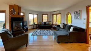 Amplia sala de estar con chimenea, un sofá, un sillón y un televisor.
