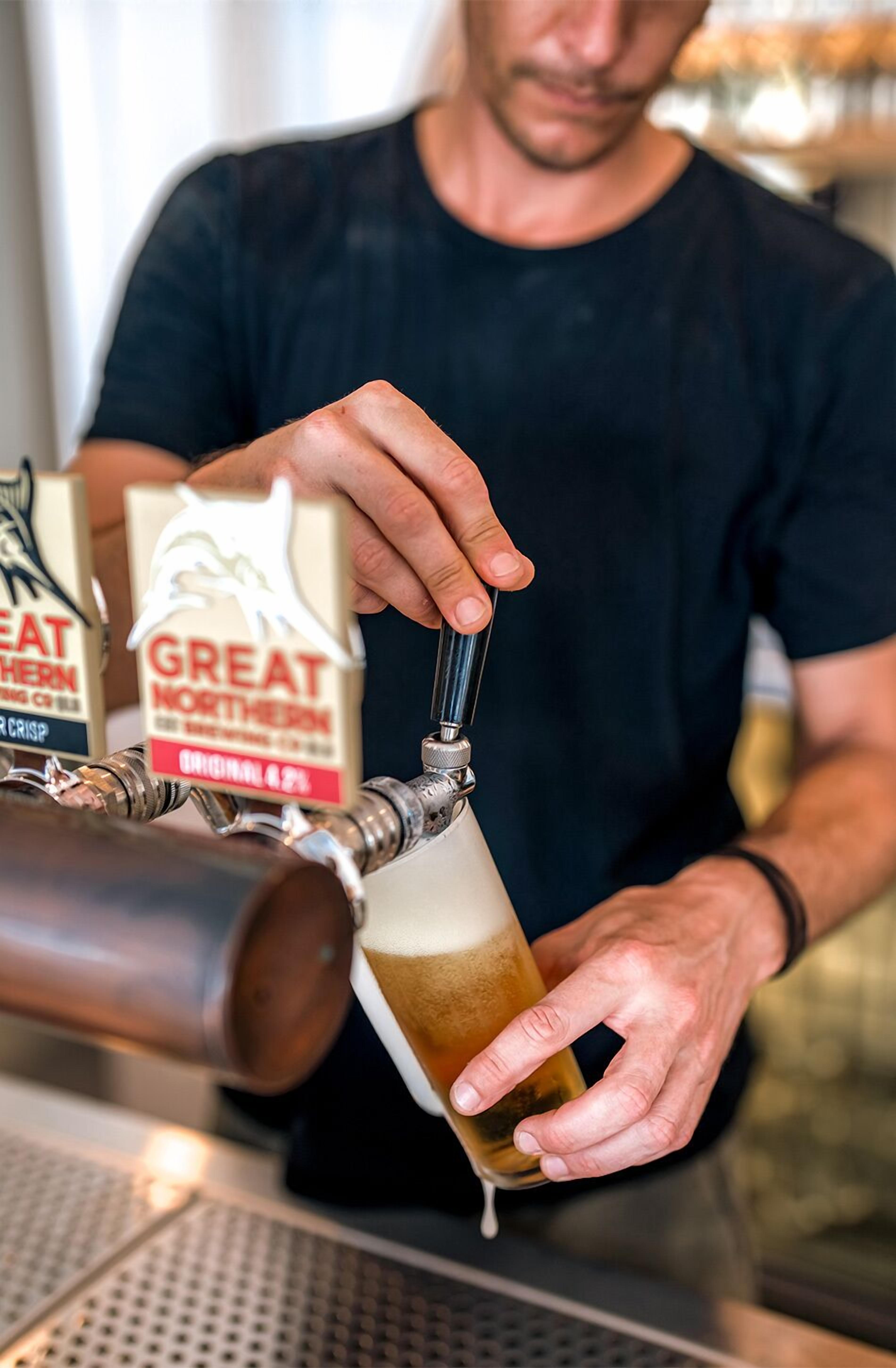 Une personne qui verse de la bière d’une tireuse dans un verre.