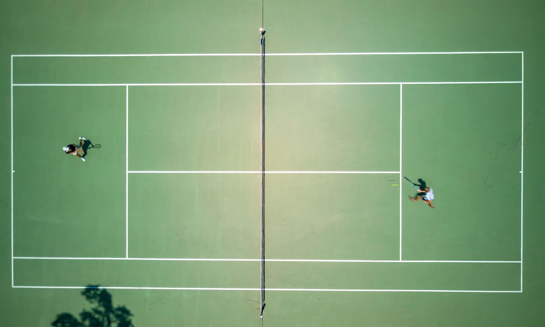 An aerial view of a tennis court with two players.