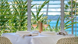 A table set for two with a white tablecloth, two wine glasses, a bottle, and a napkin folded on the table. - The Elandra (South Mission Beach)
