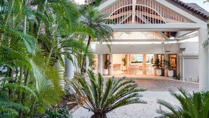 A modern building with a covered entrance, surrounded by lush tropical plants. - The Elandra (South Mission Beach)