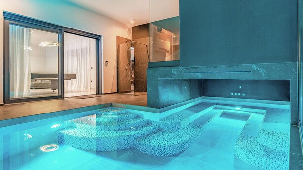 A modern bathroom with a glass-enclosed shower, a built-in fireplace, and a unique mosaic floor design. - Amazing home in Fazana with sauna (Fazana)