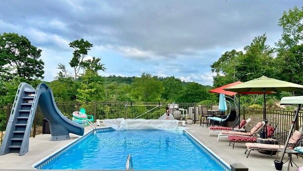 A swimming pool with a slide, lounge chairs, and a covered seating area.