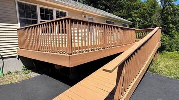 A wooden deck leading to a mobile home with a ramp.