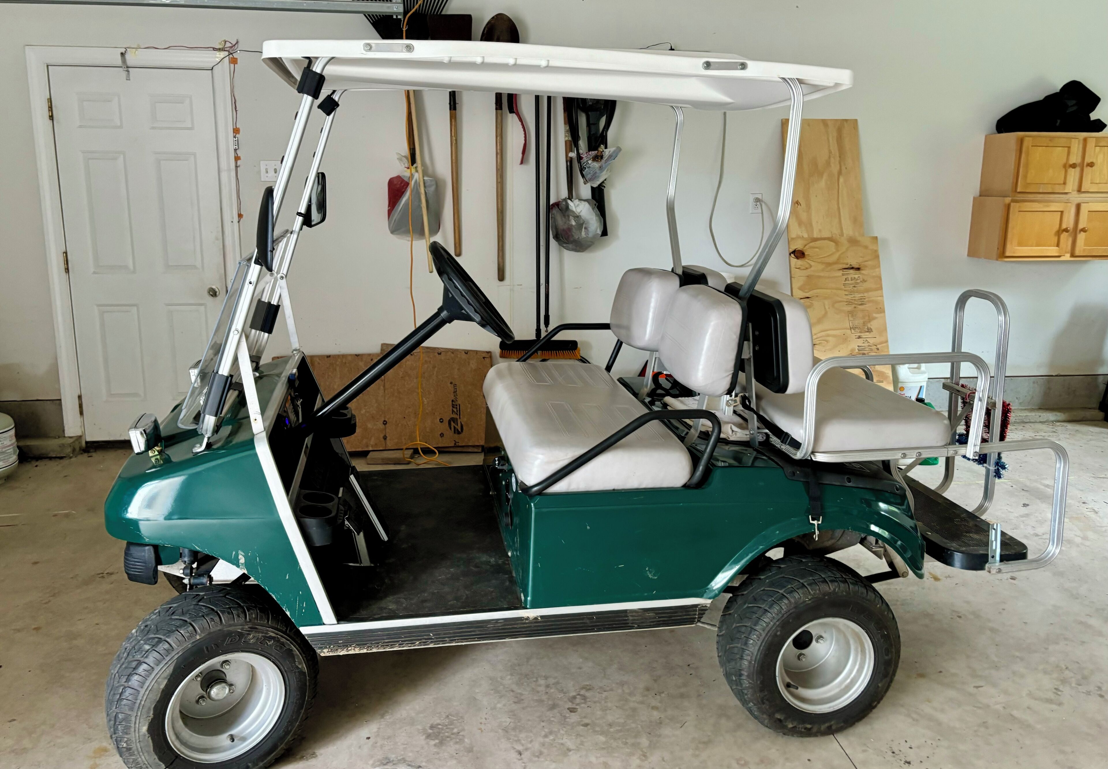 Een groene golfkar met een wit dak, geparkeerd in een binnenruimte.