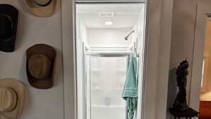 A doorway leading to a bathroom with a glass door, a wooden floor, and a towel hanging on the door. - Casa Azul - Cozy cabin centrally located downtown Bandera (Bandera)