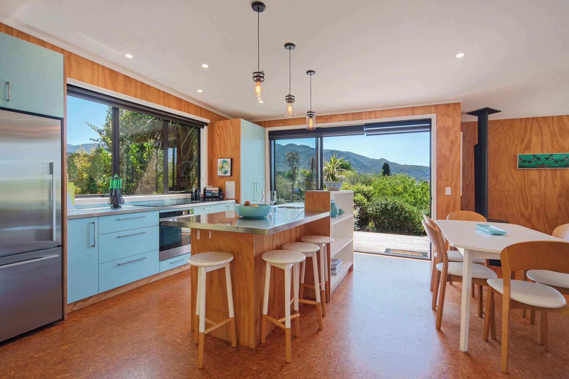 Una cocina moderna con una isla grande, taburetes de bar y un comedor con mesa y sillas.