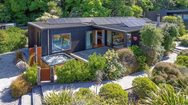 Een modern huis met een dak voorzien van zonnepanelen, een jacuzzi en een tuin.