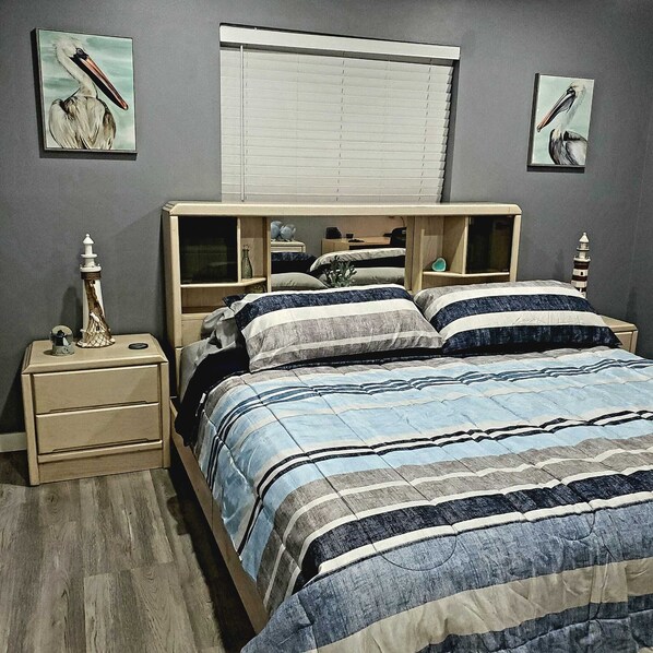 A bedroom with a bed, nightstands, and artwork on the walls.