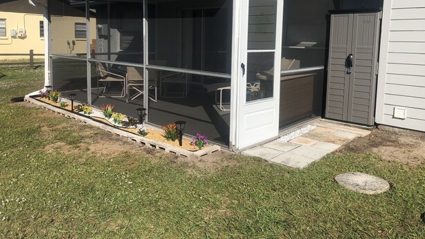 Een overdekt terras met zitplaatsen en een kleine tuin.
