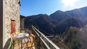 Un balcón con mesa y sillas que da a un paisaje montañoso.
