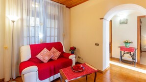 Una sala de estar acogedora con un sofá rojo, una mesita con mantel rojo y una lámpara.