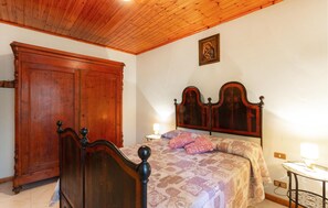 Un dormitorio con una cama de madera, un armario y una mesita de noche con lámpara.