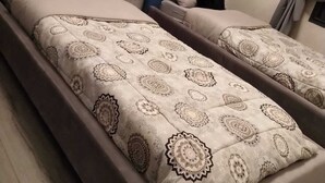 Une chambre moderne avec deux lits simples, chacun doté d’une couette à motifs et d’une tête de lit bleue.