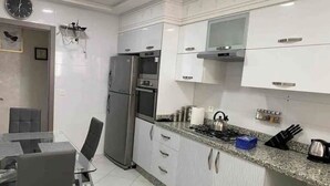 Une cuisine moderne avec des armoires blanches, des appareils en acier inoxydable et un comptoir en granit.
