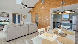 A modern living room with a sofa, dining table, and ceiling fan. - Gorgeous, Ocean View, 3 bedroom, 2 bathroom home in the heart of Kitty Hawk! (Kitty Hawk)