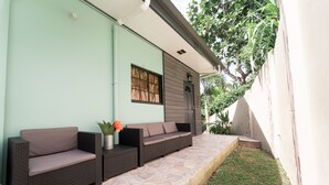 Un patio con un sofá de mimbre oscuro y una planta en maceta.
