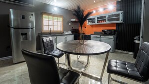 A modern kitchen with a stainless steel refrigerator, a round dining table with four chairs, and a decorative plant. - Modern two bedroom Caribbean Apartment  (Arnos Vale)