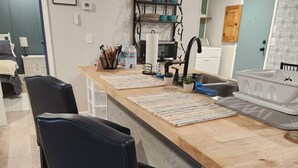 Una cocina moderna con encimera de madera, sillas negras y un lavamanos integrado.