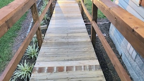 Una terraza de madera con barandillas que lleva a una casa.