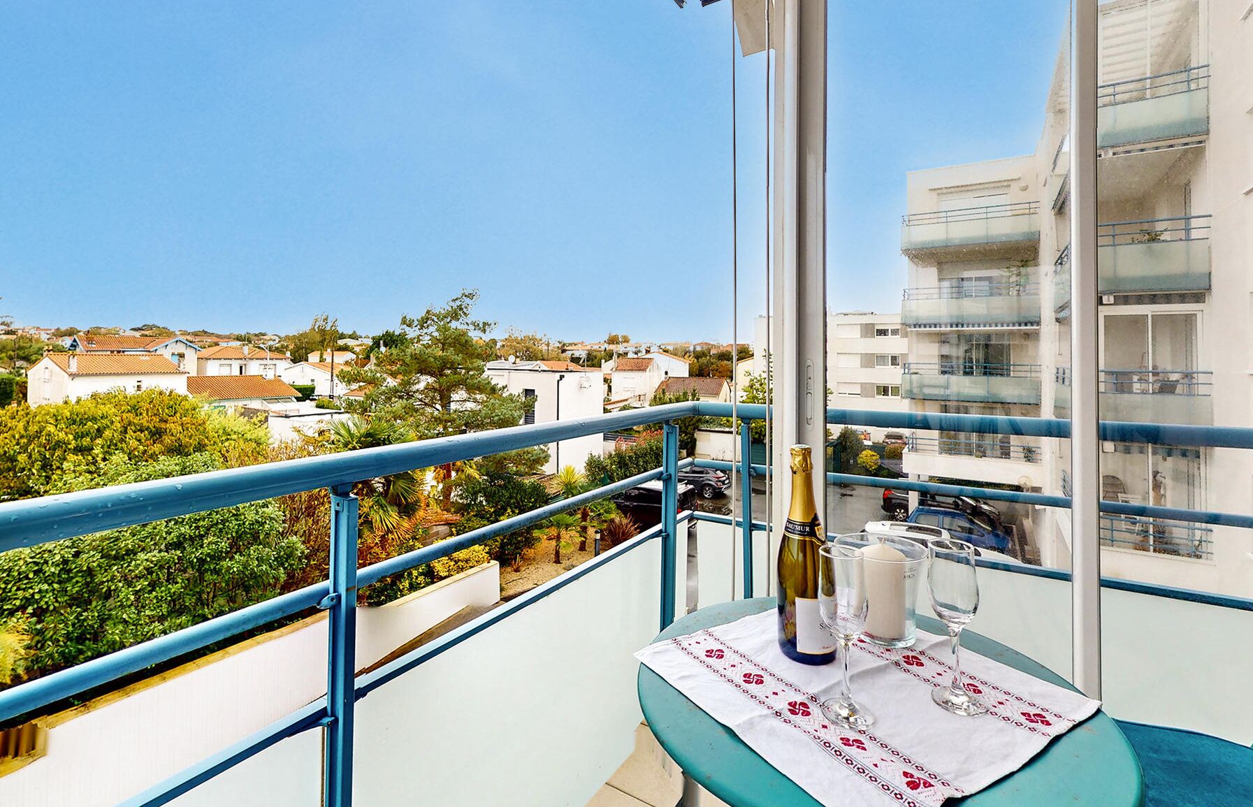 A balcony with a table set for two, a bottle of champagne, and a candle.