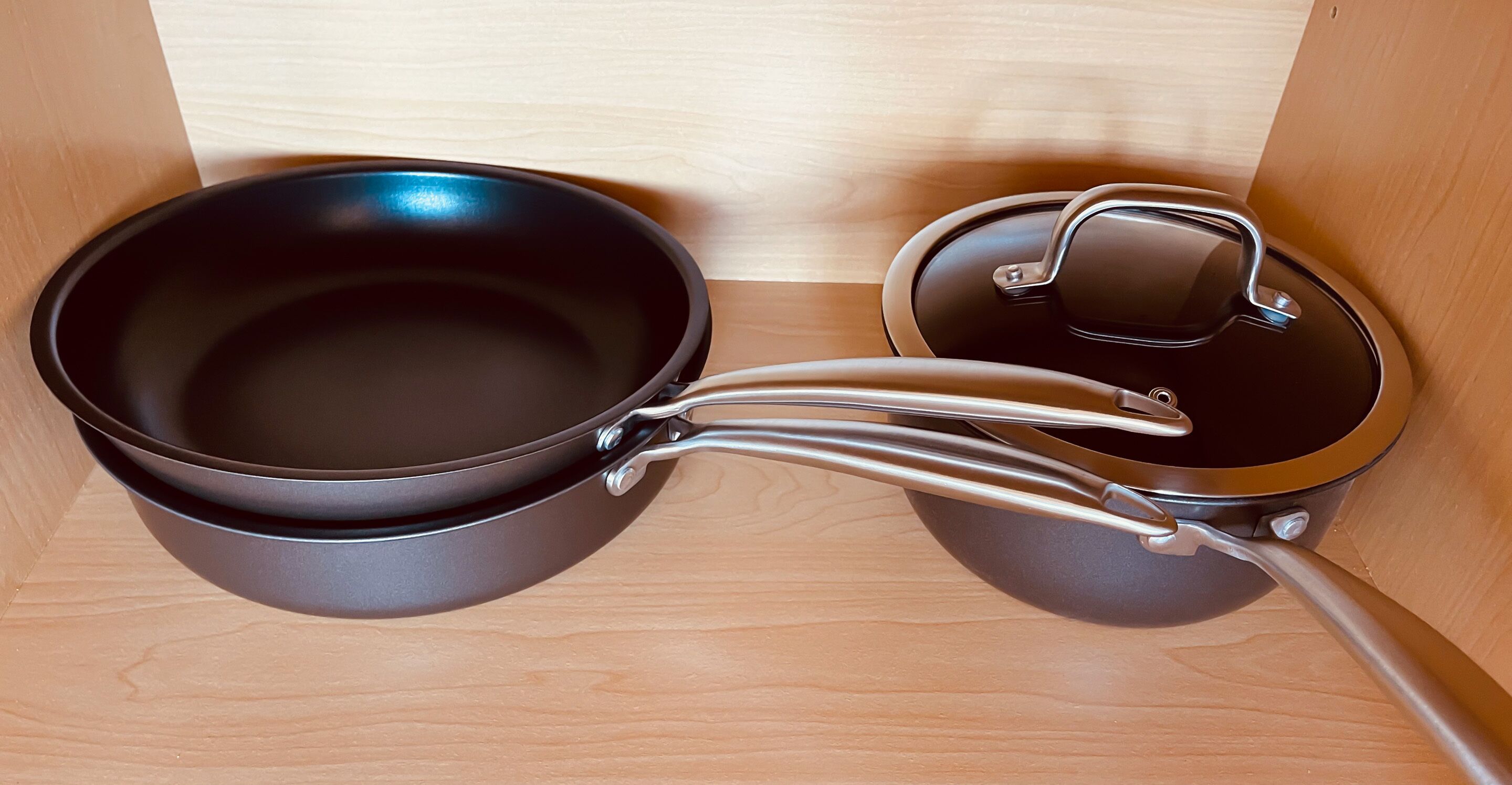 A black electric kettle with a lid and a power cord plugged into a wall socket.