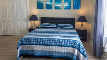 Un dormitorio con una cama, dos mesitas de noche, un cabecero y tres cuadros colgados en la pared.