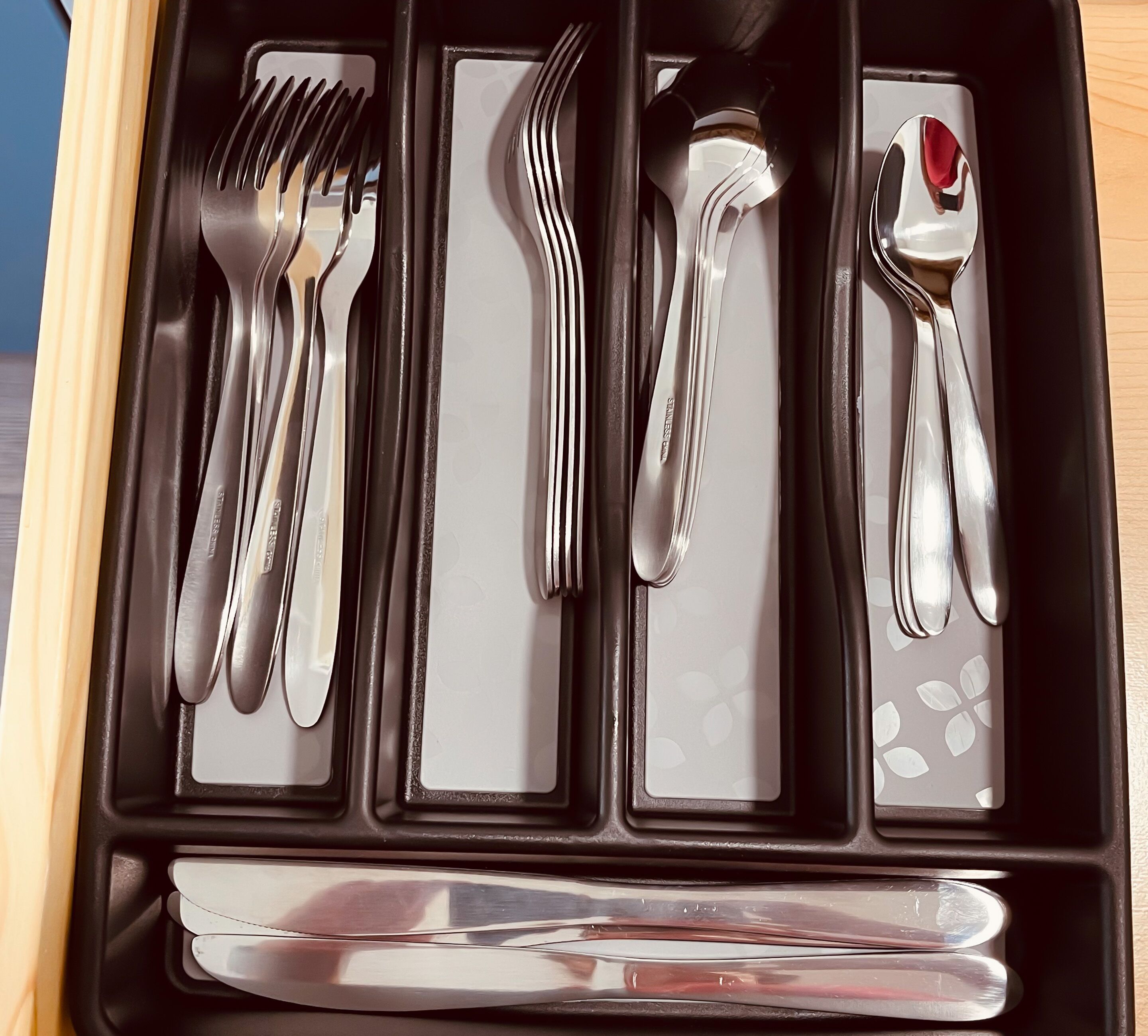 A drawer containing various stainless steel cutlery including forks, spoons, and a knife.