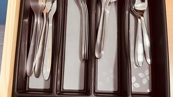 A drawer containing various stainless steel cutlery including forks, spoons, and a knife.