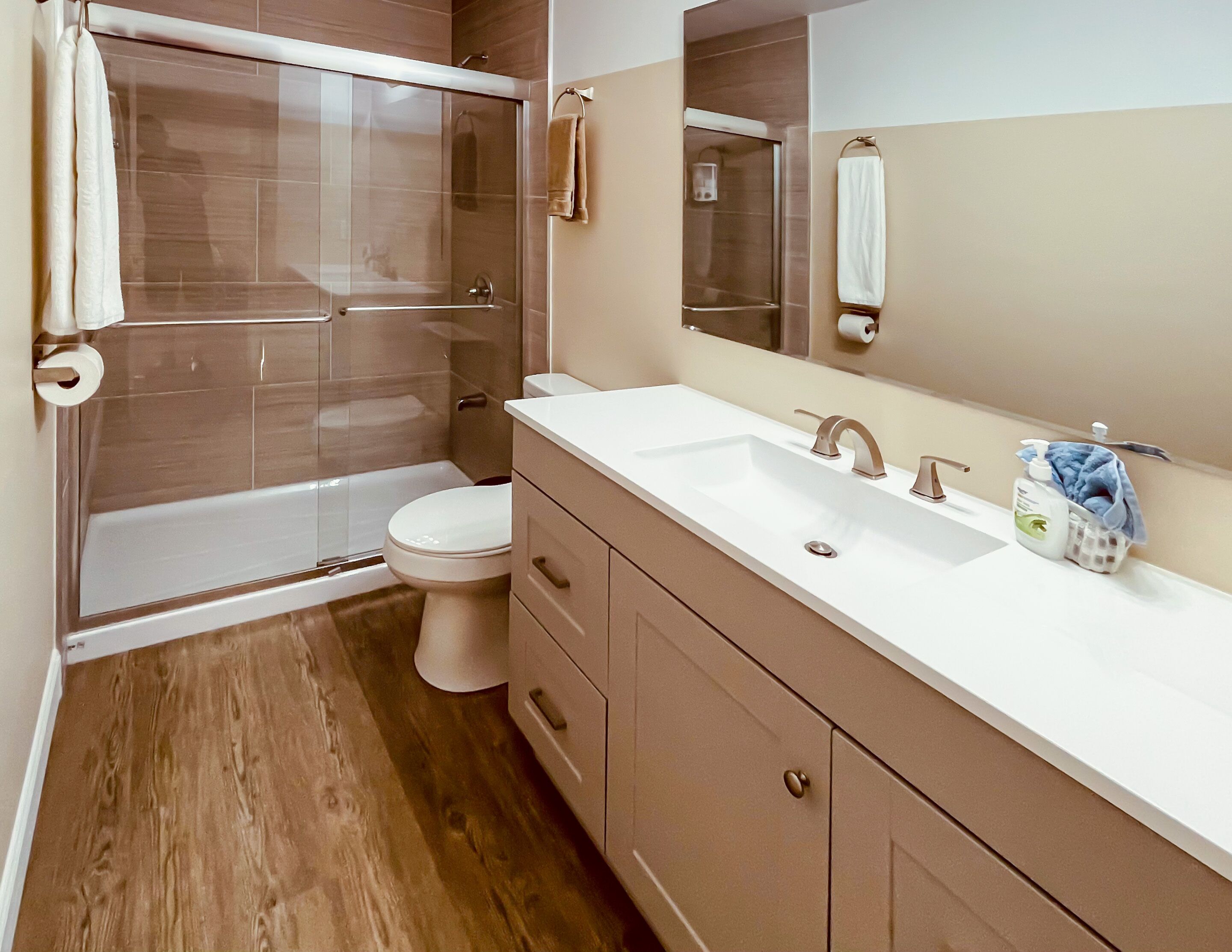 Une salle de bain moderne avec une douche à parois de verre, des toilettes blanches et un meuble-lavabo avec un évier et un miroir.
