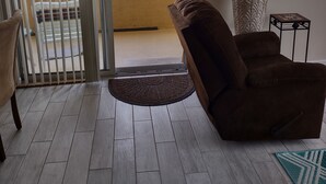 A room with a sliding glass door leading to a balcony, a brown armchair, a lamp, and a small table. - 1st Floor Condo,  $85 OctNovDec. Sleeps 4. renovated.
The Avalon at Clearwater

 (Clearwater)